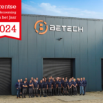 Een groepsfoto van Betech-medewerkers die buiten de Betech-productiefaciliteit staan met een banner 'Drentse Onderneming van het Jaar 2024' die prominent boven hen hangt.